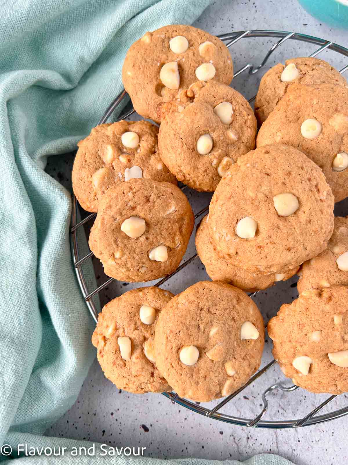 White chocolate chip cookies with macadamia nuts on a wire rack.