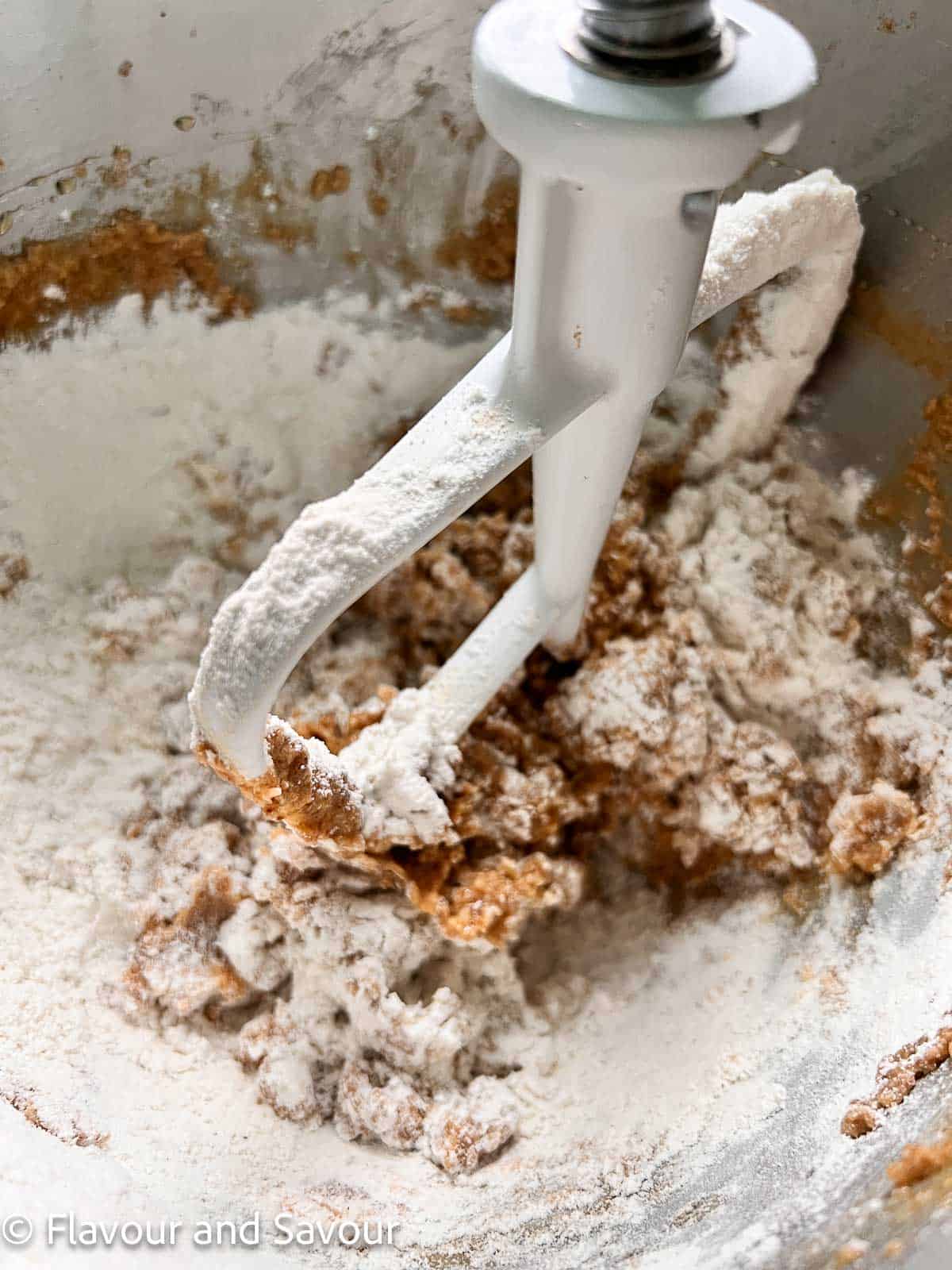 Adding dry ingredients to creamed butter and sugar in a stand mixer.