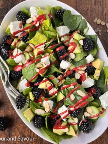 Blackberry Spinach Salad with blackberry dressing drizzled on top.