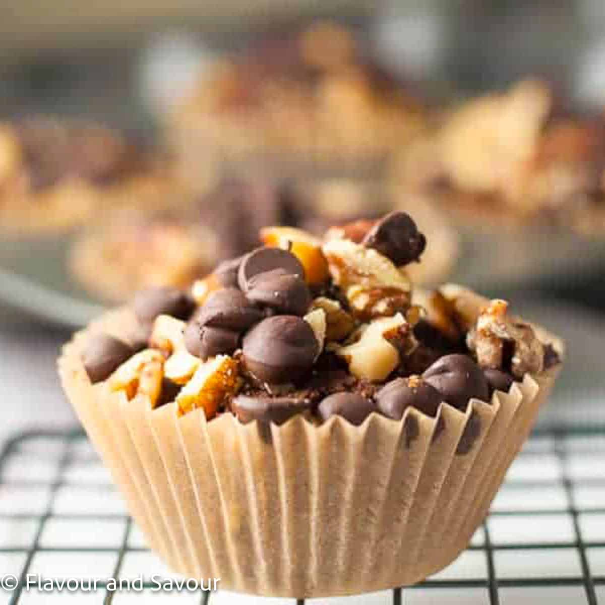 A chunky monkey muffins in a muffin liner topped with chocolate chips and chopped walnuts.