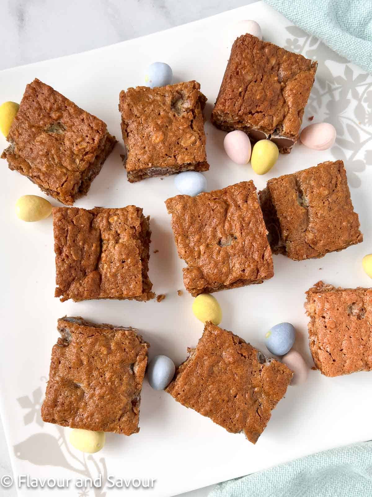 Mini egg oatmeal cookie bars cut into squares on a plate with mini eggs.