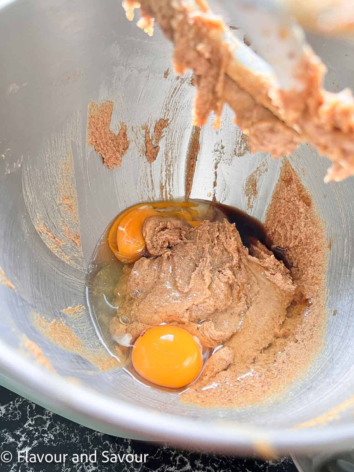 Adding eggs and vanilla to butter and sugar mixture in a stand mixer.