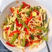 A bowl of Thai-style coleslaw with Napa cabbage, carrots red bell pepper, sugar snap pea pods and green onions.